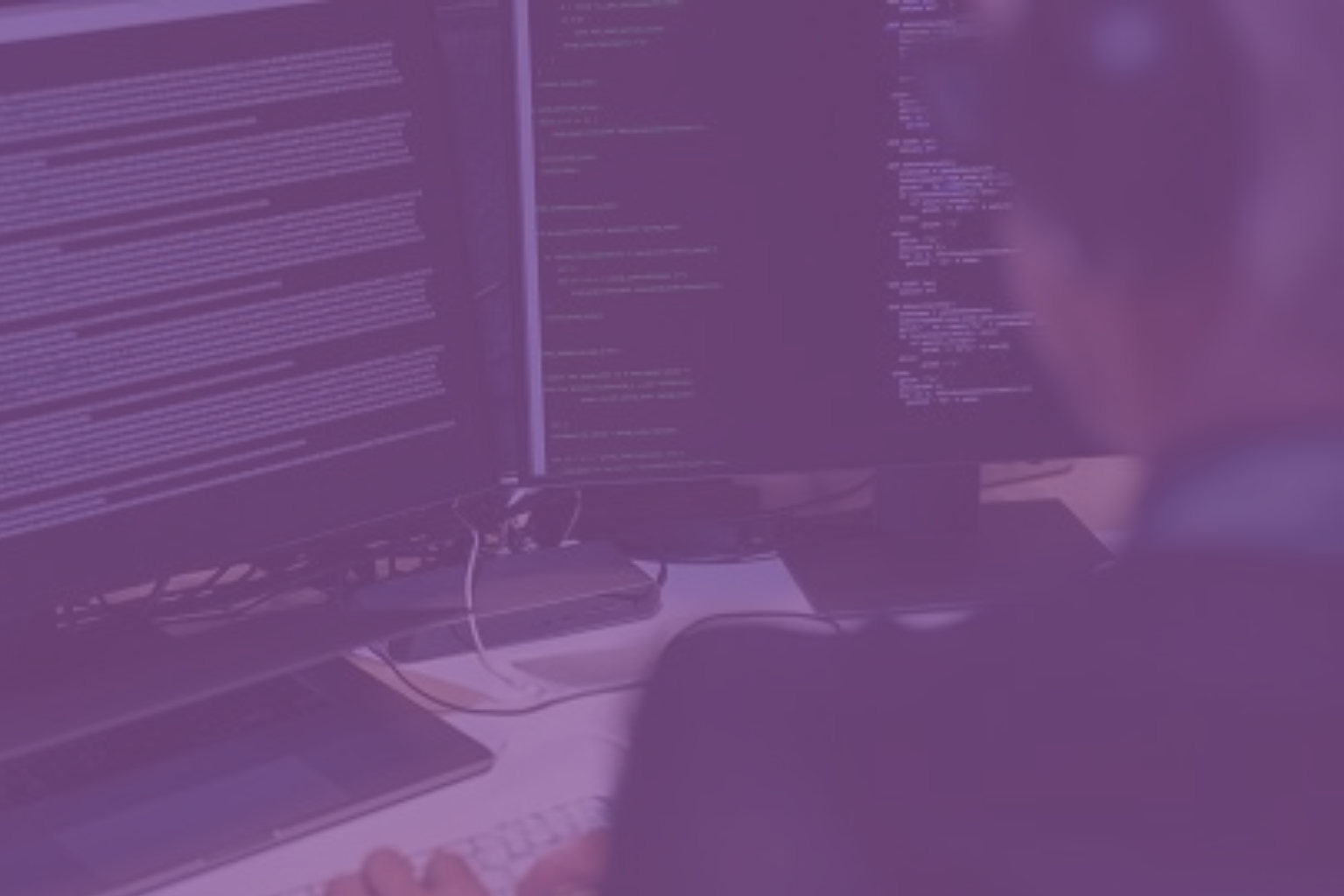Persona frente a varios monitores con código, representando la importancia de proteger los datos de tu empresa según el RGPD